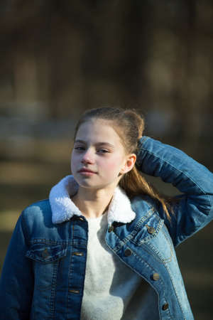 Portrait of a schoolgirl in a denim jacket outdoors.の写真素材