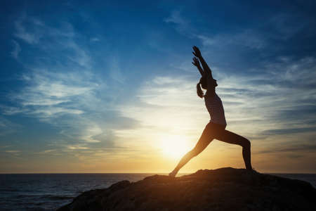 Silhouette young meditation woman practicing yoga on the ocean beach at amazing sunset. Fitness and...