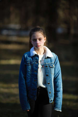 Portrait of a twelve-year-old sweet girl in a denim jacket, photoshooting in the spring Park.の写真素材