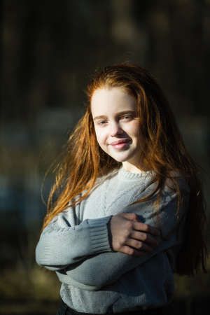 Portrait of attractive cheerful teen girl with bright red long hair, photoshooting in the spring Park.の写真素材