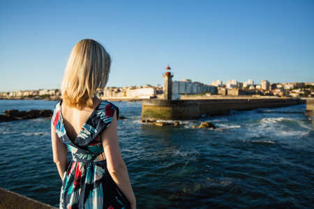 Beautiful blonde woman in a long dress standing on the seafront.の写真素材