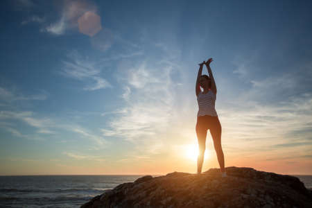 Silhouette fitness yoga girl on the background of the sea morning exercises meets the dawn. Healthy lifestyle.の写真素材