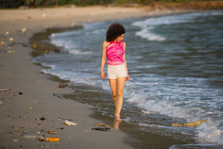 Asian woman walks along a polluted tropical beach. Pollution and environmental problems.の写真素材