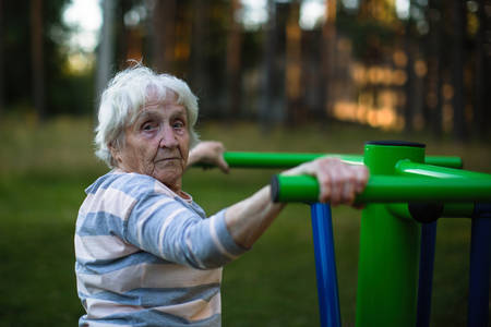 Old woman doing exercise on the street sport playground.の写真素材