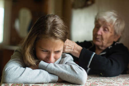 A crying little girl is comforted by her grandmother.の写真素材