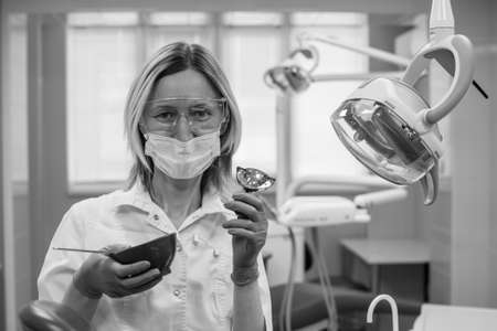 Portrait of female dentist with tools over medical office background. Black and white photo..の写真素材