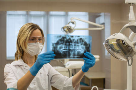 Dentist woman in dental office stares at x-ray image of jaw.の写真素材