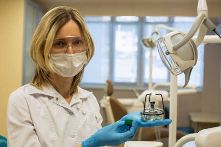 Female dentist doctor holding alcohol burner or spirit lamp in dental clinic. Laboratory equipment,...