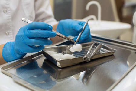 Female dentist hands holding dental tools over medical office background. Medicine, stomatology and healthcare concept.の写真素材
