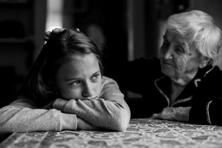 Old woman comforting a crying little girl granddaughter. Black-and-white photo.の写真素材