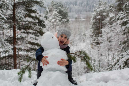 Little girl with snowman in winter snowy Park.