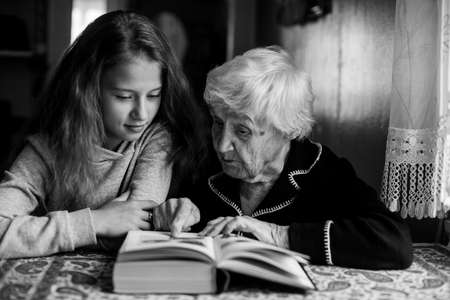 An old granny with a little girl reading a book.の写真素材