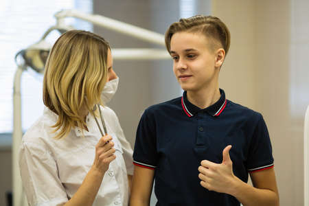 Woman dentist with a young man patient in dental room.の写真素材