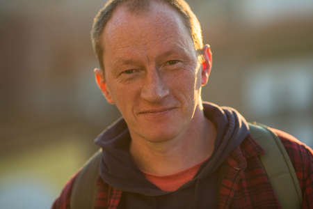 Close-up portrait of a man on the street in the background light.