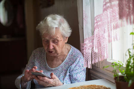 An old woman with a smartphone in her hands.