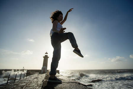 Playful young woman in spring having fun and dancing of sea promenade. の写真素材