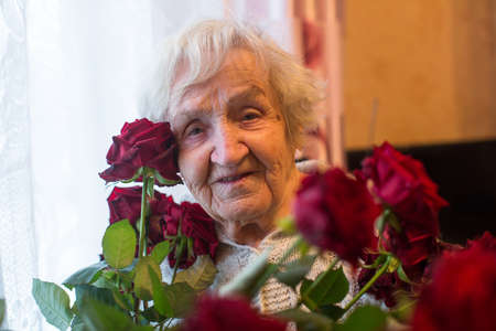 Old woman with flowers in the her house. Granny.