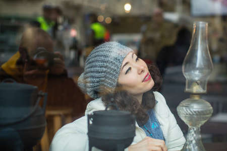Multicultural asian woman posing for a photographer (reflection in the glass) looks out from behind...