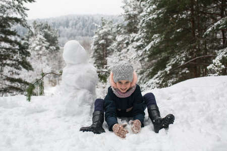 Cute little girl with snowman in winter snowy Park.の写真素材
