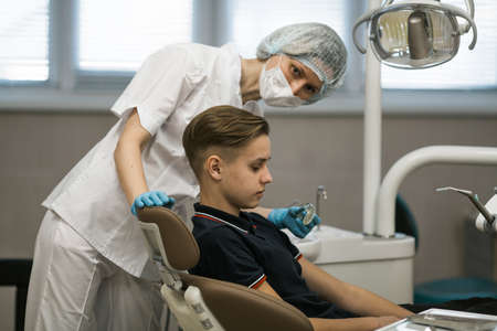 Female dentist puts on a guy patient a mouth guard in dental office.の写真素材
