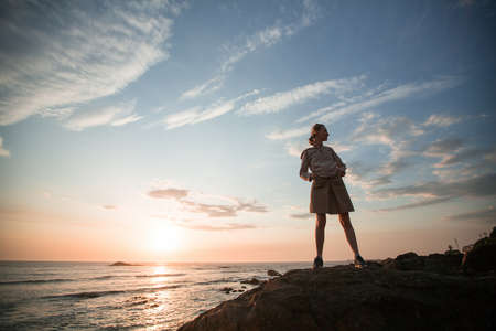 Woman stands on the rocky Atlantic ocean coast during amazing sunset.の写真素材