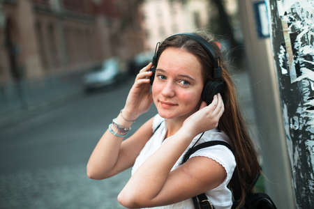 Girl on the street enjoying music with headphones.の写真素材