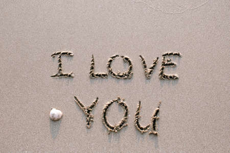I Love You - drawn on sand beach with the wave.の写真素材