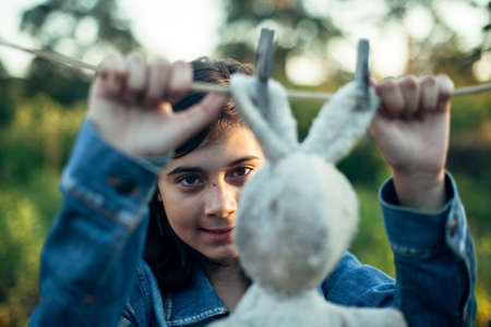A teenage girl dries a toy hare on a clothesline.の写真素材