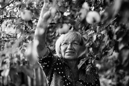 Black and white photo of aged woman in her garden.