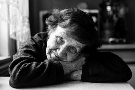 Black and white portrait of old woman in her home.
