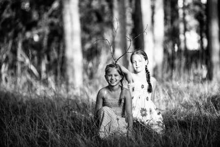 Two ten year old girls pose for a photo in the park. Black and white photo.の写真素材