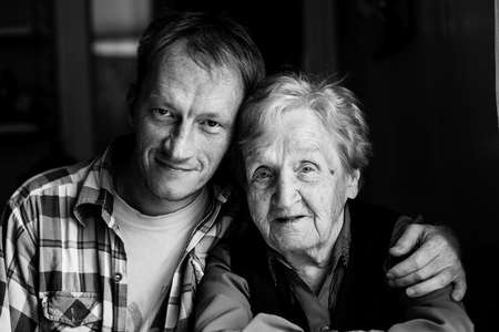 Portrait of man embracing his old grandmother. Black and white photo.の写真素材