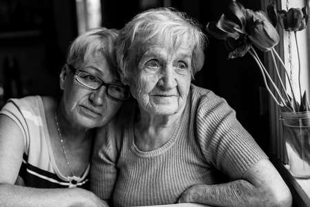 An old woman with her adult daughter. Black and white photography.