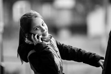 Little girl talking on phone in the street. Black and white photography.の写真素材