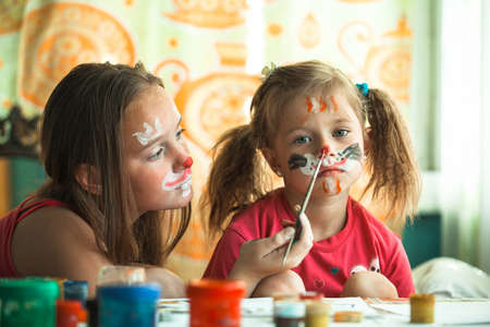 Young sisters playing with painting faces.の写真素材