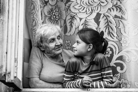 An old woman and granddaughter together to look out the window. Black and white photography.の写真素材