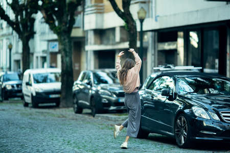 Young woman dancing in the middle of the pavement.