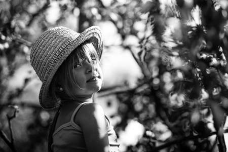 Little girl in a straw hat in the park. Black and white photo.
