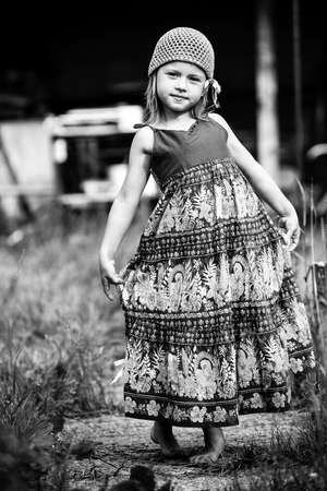 Five-year girl posing for the camera in the yard of a village house. Black and white photo.の写真素材