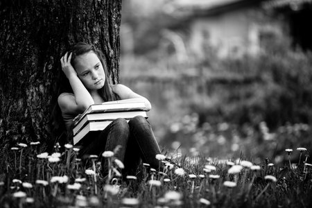 Tired teen girl with books in the park. Black and white photo.の写真素材