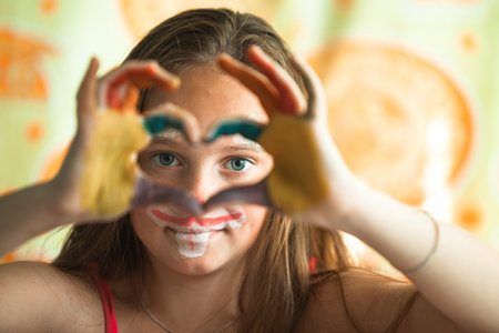 Hand painted girl, fingers folded in the form of heart.