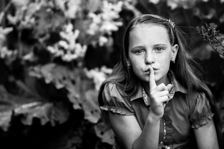 Hushing. Teen girl with her finger over her mouth. Black and white photo.の写真素材
