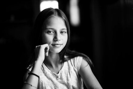 Portrait of teen girl sitting at the table. Black and white photo.の写真素材
