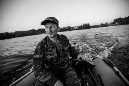 Fisherman on rubber motor boat floats on the lake. Black and white photo.の写真素材