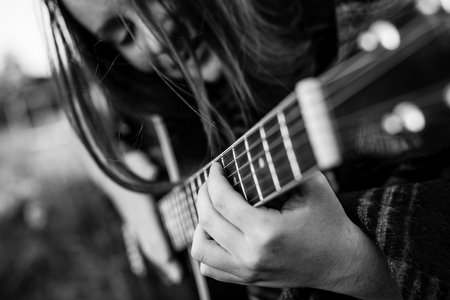 Close-up fingers on the strings, girl playing acoustic guitar. Black and white photo.の写真素材