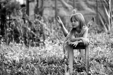 Little girl in the yard of a country house. Black and white photo.の写真素材