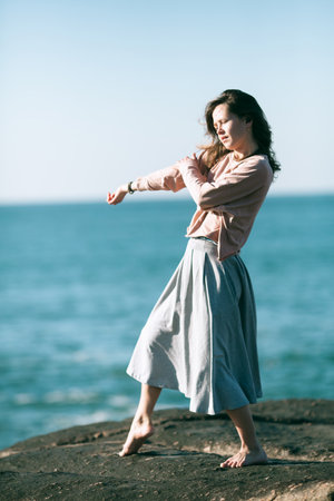 A woman is engaged in choreography on the ocean coast.の写真素材