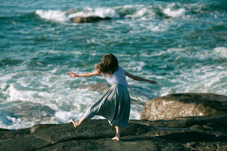 Woman dancer is engaged in choreography on the ocean coast.の写真素材