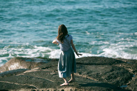 The dancer woman is engaged in choreography on the rocky Alantic coast.の写真素材