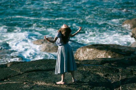 Dancer woman is engaged in choreography on the rocky coast of the ocean.の写真素材
